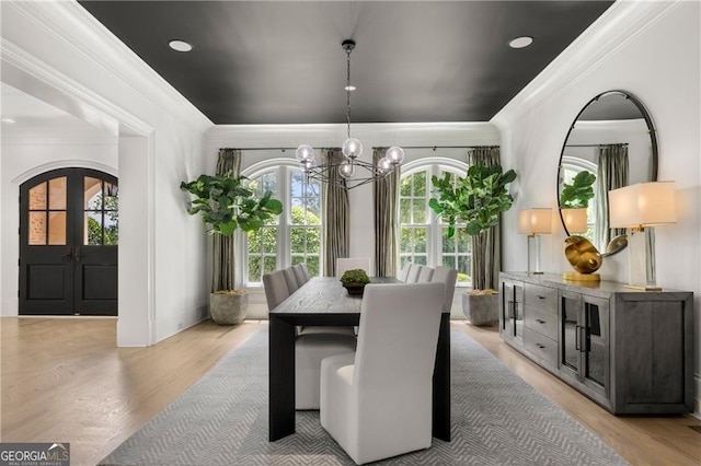 dining space with a healthy amount of sunlight, an inviting chandelier, french doors, and light hardwood / wood-style floors