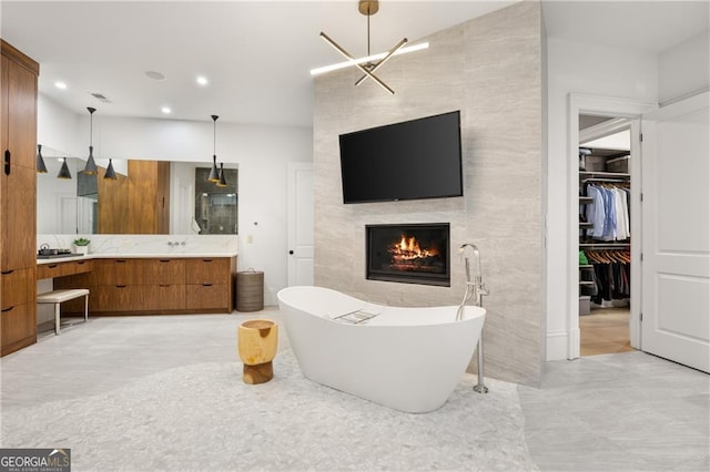 interior space with a large fireplace, a bathtub, a notable chandelier, and vanity