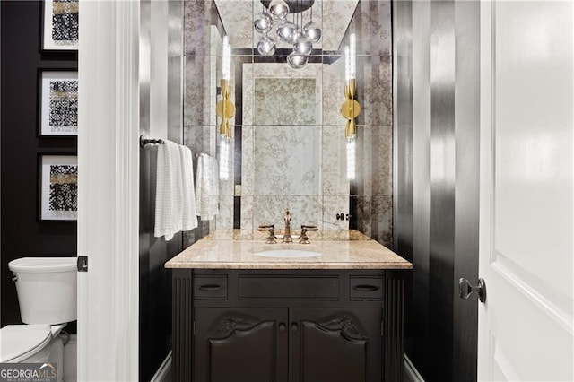 bathroom with vanity, toilet, and a notable chandelier