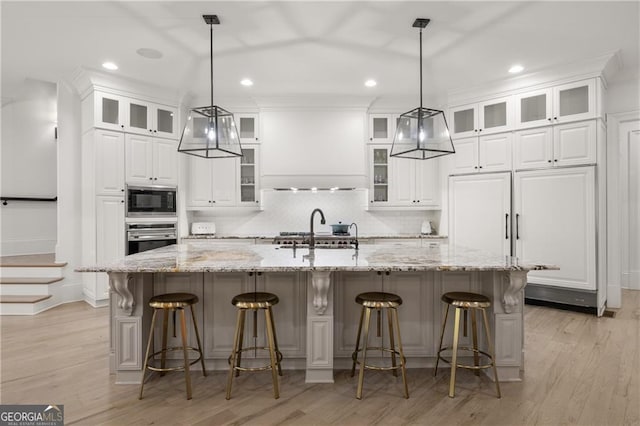 kitchen with white cabinets, a kitchen bar, a spacious island, and light hardwood / wood-style flooring