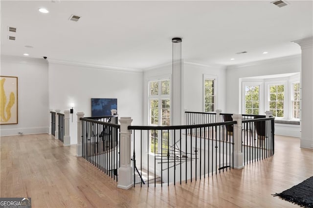 corridor featuring ornamental molding, plenty of natural light, and light hardwood / wood-style floors