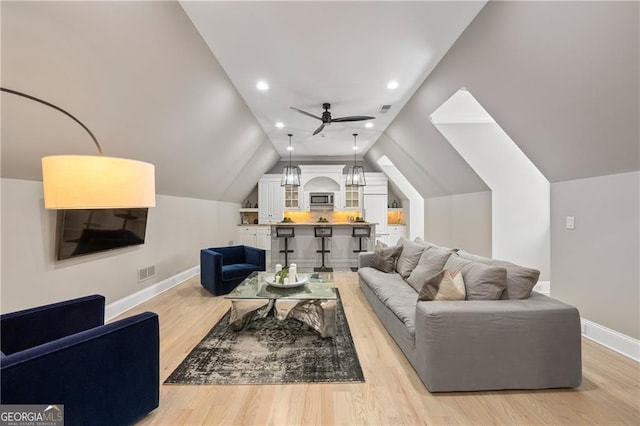 living room featuring ceiling fan, light wood-type flooring, and vaulted ceiling