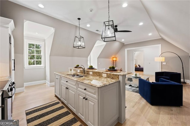 kitchen featuring light wood-type flooring, white cabinets, a center island with sink, and sink