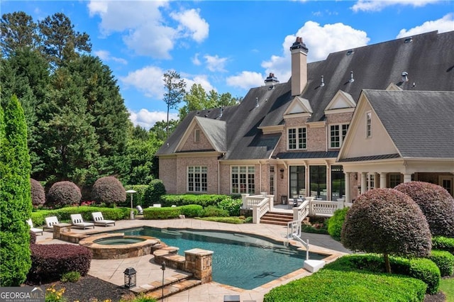 back of property with a patio and a pool with hot tub