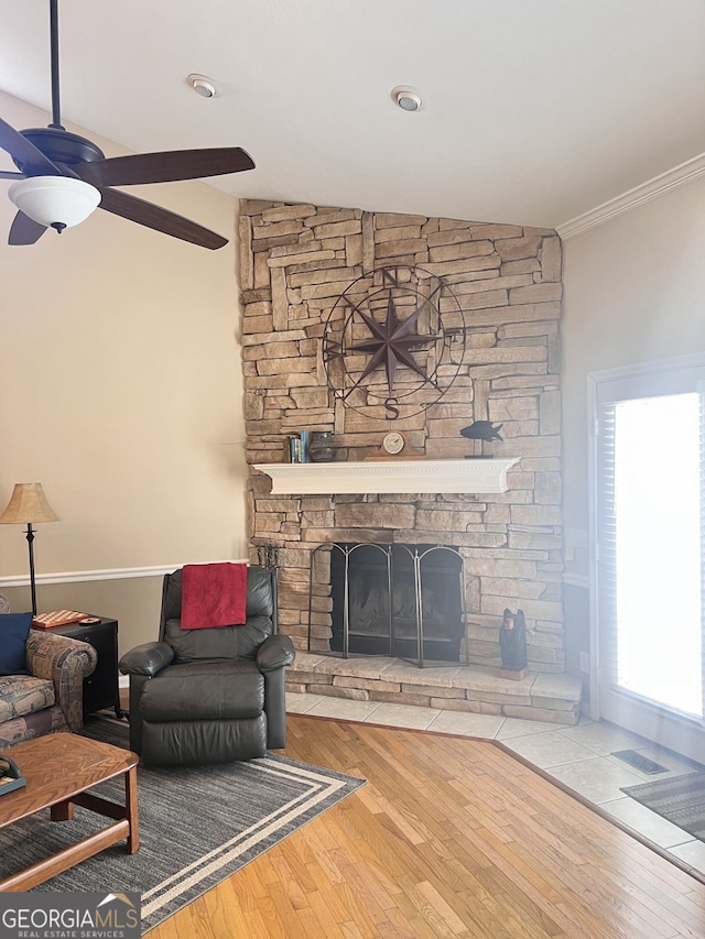 living room featuring a fireplace, crown molding, lofted ceiling, wood-type flooring, and ceiling fan