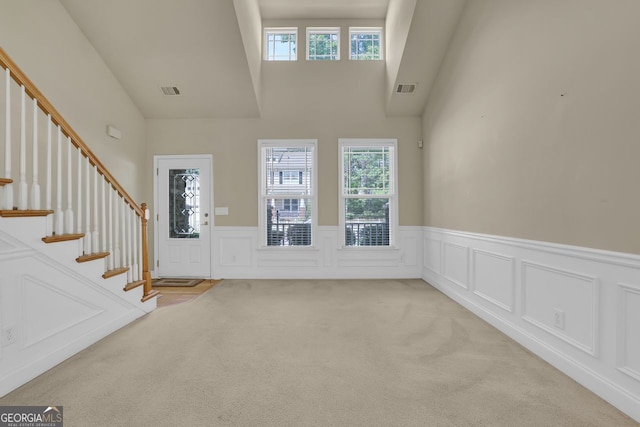 carpeted entryway featuring a high ceiling