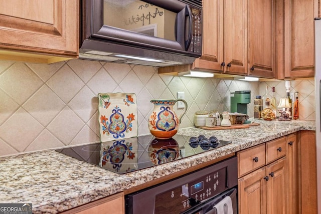 kitchen featuring black appliances, backsplash, and light stone countertops