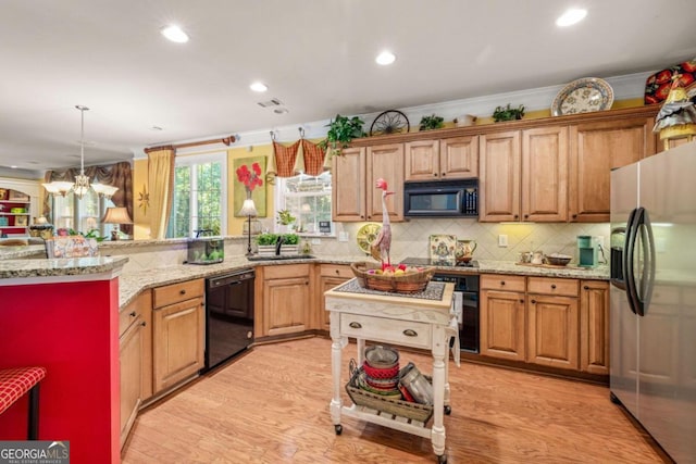 kitchen with an inviting chandelier, light wood-type flooring, light stone counters, black appliances, and ornamental molding