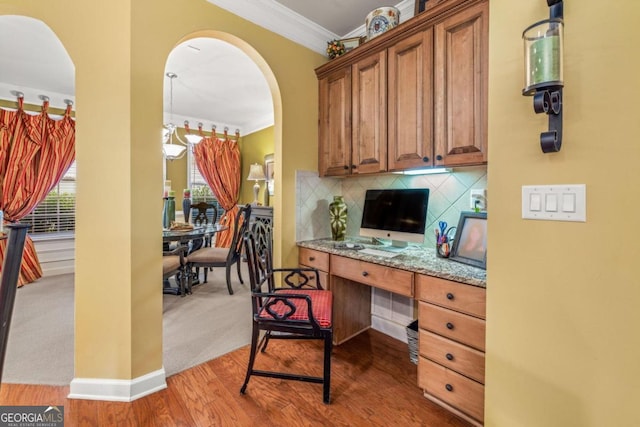 office with crown molding, built in desk, an inviting chandelier, and carpet