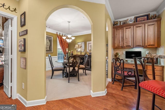 interior space with light wood-type flooring, pendant lighting, crown molding, and a notable chandelier