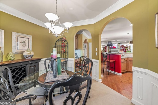 dining room featuring light wood-type flooring, crown molding, and a notable chandelier