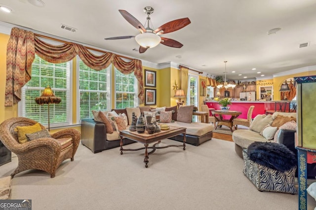 carpeted living room featuring ceiling fan with notable chandelier and crown molding