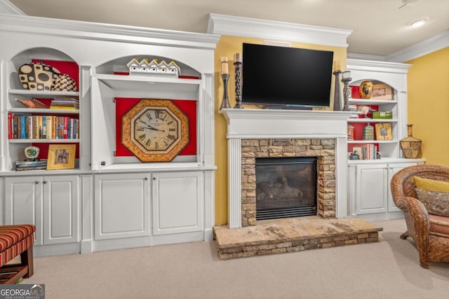 living room with built in shelves, carpet flooring, ornamental molding, and a stone fireplace