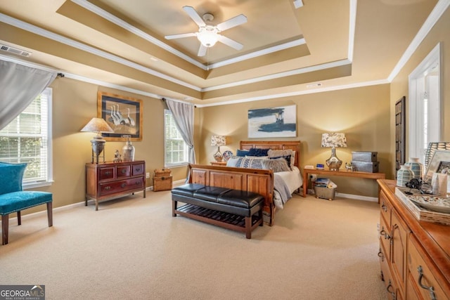 carpeted bedroom with ornamental molding, multiple windows, a tray ceiling, and ceiling fan