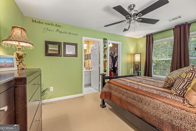 bedroom with ensuite bath, a walk in closet, ceiling fan, and a closet