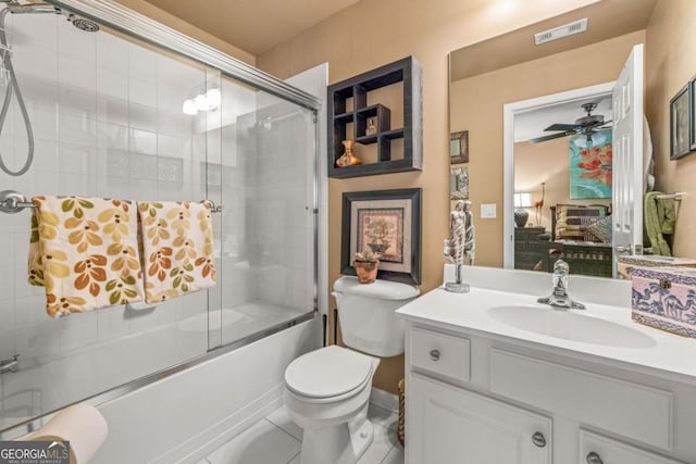 full bathroom featuring toilet, tile patterned floors, vanity, ceiling fan, and bath / shower combo with glass door