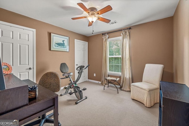 exercise room with light colored carpet and ceiling fan