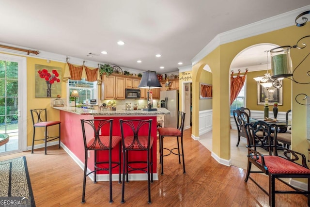 kitchen featuring plenty of natural light, a breakfast bar, and light hardwood / wood-style flooring