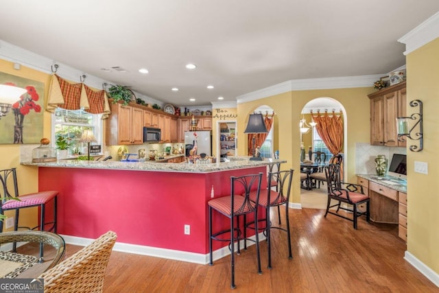 kitchen with a kitchen bar, plenty of natural light, light hardwood / wood-style floors, and kitchen peninsula