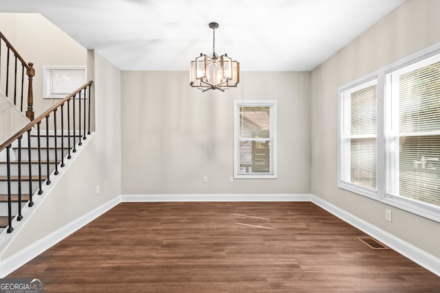 unfurnished dining area featuring dark hardwood / wood-style floors and a notable chandelier