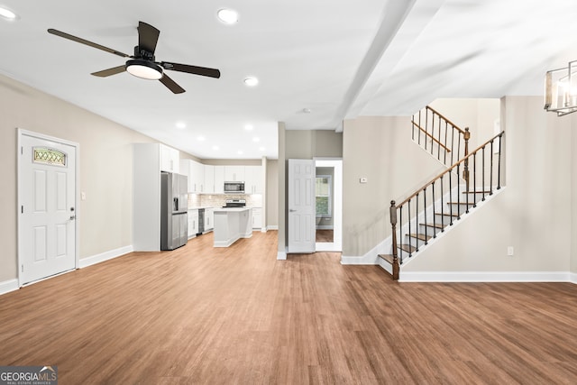 unfurnished living room with light wood-type flooring and ceiling fan