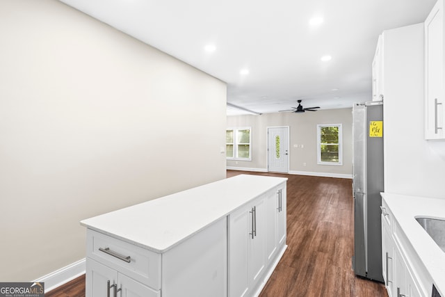 kitchen featuring dark wood-type flooring, white cabinets, ceiling fan, and stainless steel fridge