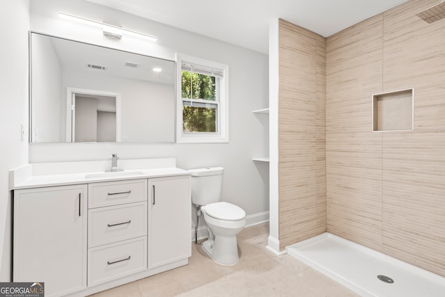 bathroom featuring vanity, toilet, a tile shower, and tile patterned floors