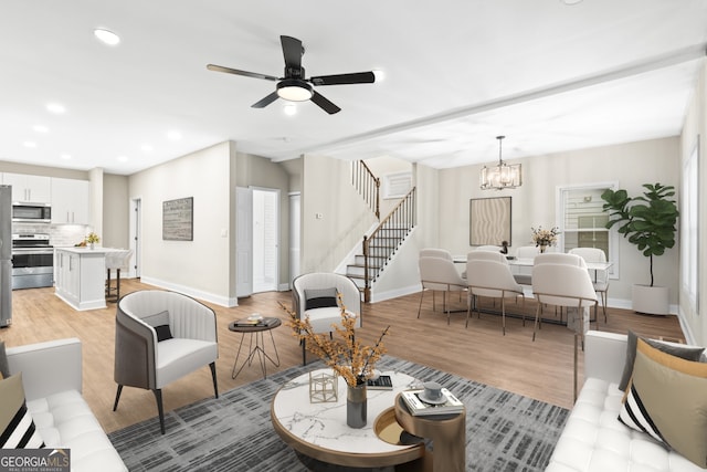 living room featuring ceiling fan with notable chandelier and light hardwood / wood-style flooring