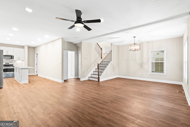 unfurnished living room featuring ceiling fan with notable chandelier and light hardwood / wood-style floors