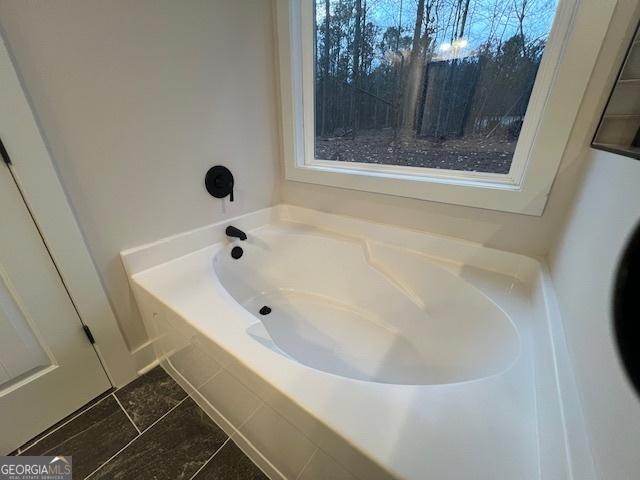 bathroom with tiled bath and tile patterned floors