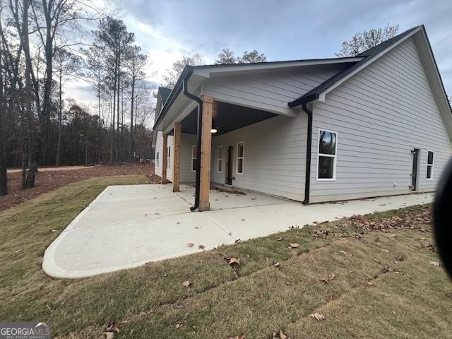 rear view of property with a lawn and a patio