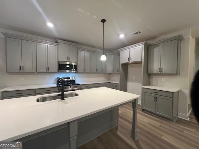 kitchen featuring appliances with stainless steel finishes, dark wood-type flooring, sink, gray cabinets, and hanging light fixtures