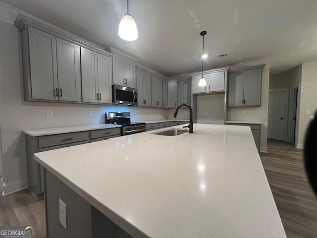 kitchen with pendant lighting, dark hardwood / wood-style flooring, stainless steel appliances, and sink