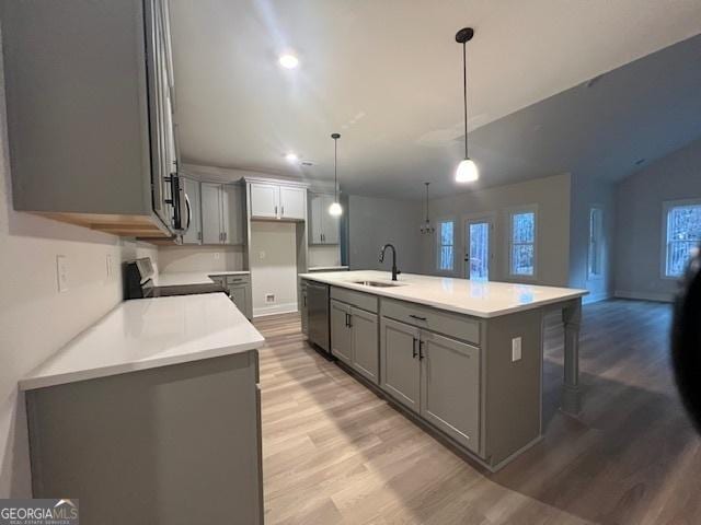 kitchen featuring light wood-type flooring, a center island with sink, hanging light fixtures, and sink