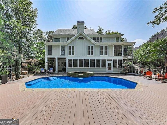 view of pool featuring a wooden deck, a sunroom, a patio area, and an in ground hot tub