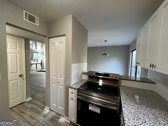 kitchen featuring tasteful backsplash, visible vents, stainless steel electric stove, wood finished floors, and white cabinetry