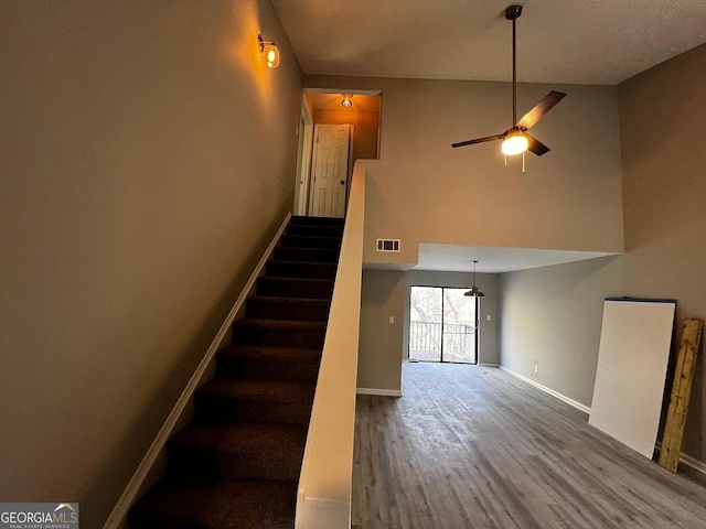 staircase with ceiling fan, wood finished floors, visible vents, and baseboards