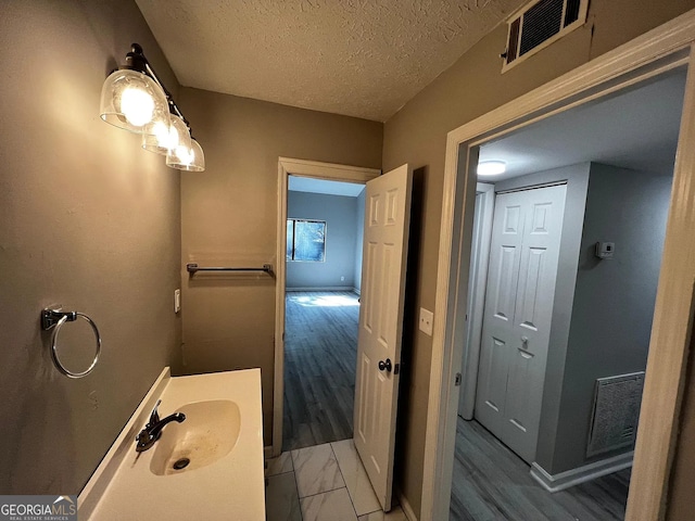 bathroom featuring visible vents, a textured ceiling, wood finished floors, and vanity