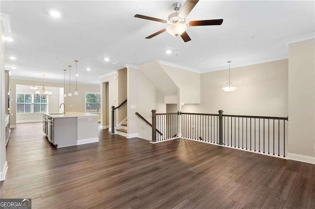 unfurnished living room with ceiling fan with notable chandelier, dark hardwood / wood-style floors, sink, and ornamental molding