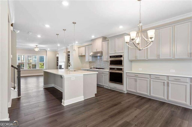 kitchen with ceiling fan with notable chandelier, pendant lighting, stainless steel appliances, and dark wood-type flooring