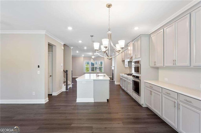 kitchen featuring dark hardwood / wood-style floors, decorative light fixtures, an inviting chandelier, an island with sink, and crown molding