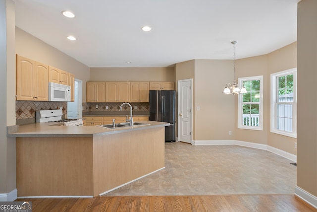 kitchen with white appliances, pendant lighting, light hardwood / wood-style flooring, sink, and a chandelier