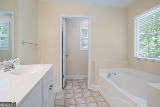 bathroom featuring tile patterned flooring, plenty of natural light, a bathtub, and vanity