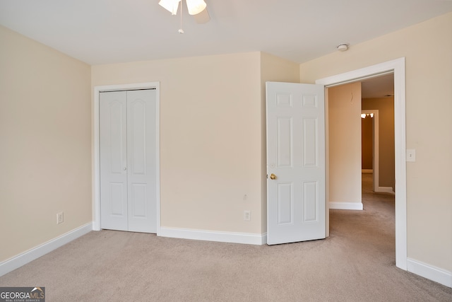 unfurnished bedroom featuring light colored carpet, ceiling fan, and a closet