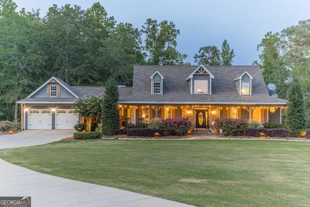 cape cod house with covered porch, a lawn, and a garage