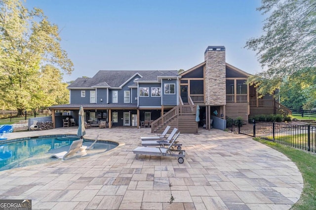 rear view of house with a fenced in pool and a patio area