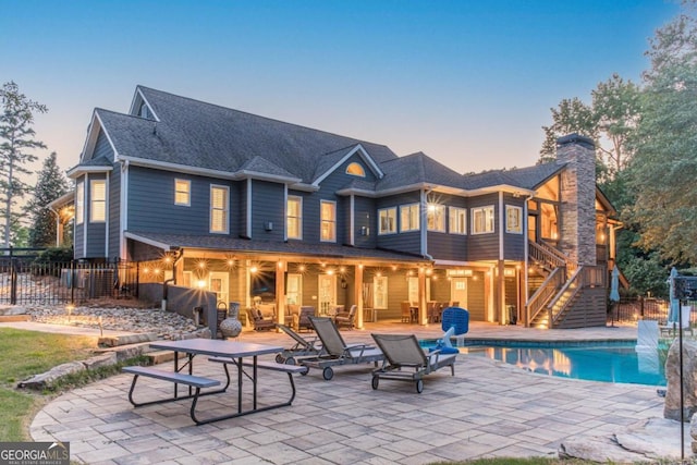 back house at dusk with a fenced in pool and a patio area