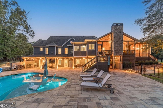 pool at dusk featuring a hot tub and a patio