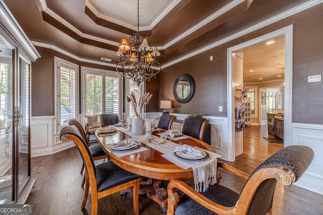 dining area with wood-type flooring, a raised ceiling, a chandelier, and crown molding