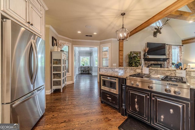 kitchen featuring dark hardwood / wood-style floors, decorative light fixtures, a stone fireplace, stainless steel appliances, and light stone counters